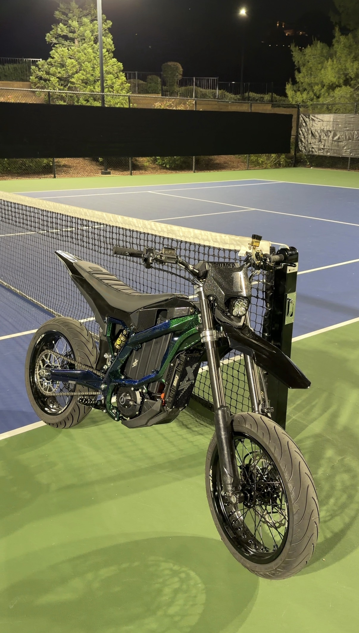 Customized Surron Ultra Bee electric moto on a lit court at night